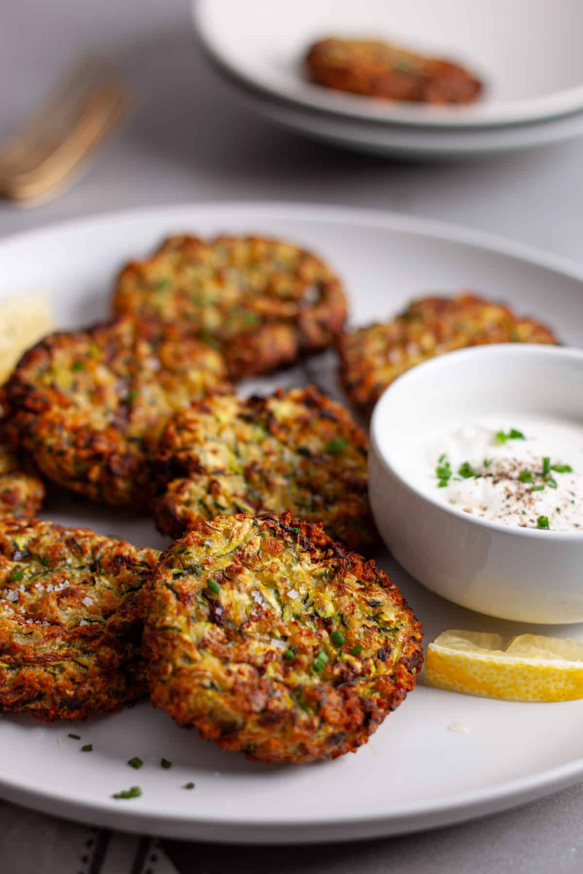 A close up of a platter of golden brown zucchini fritters.