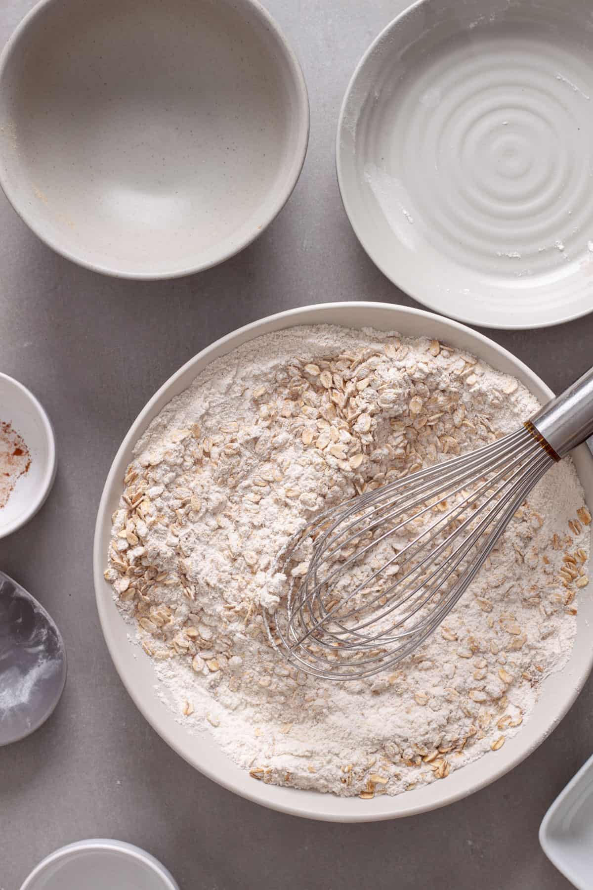 Dry ingredients for banana oat muffins in a mixing bowl with a whisk.