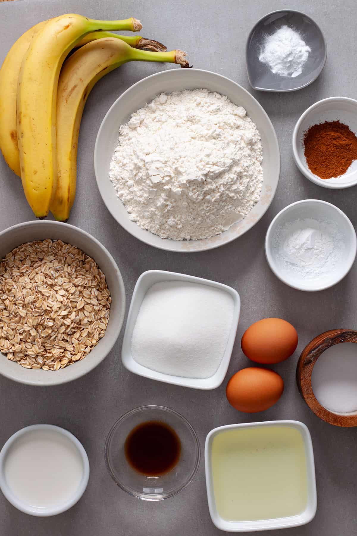 Ingredients for banana oat muffins on a gray table.