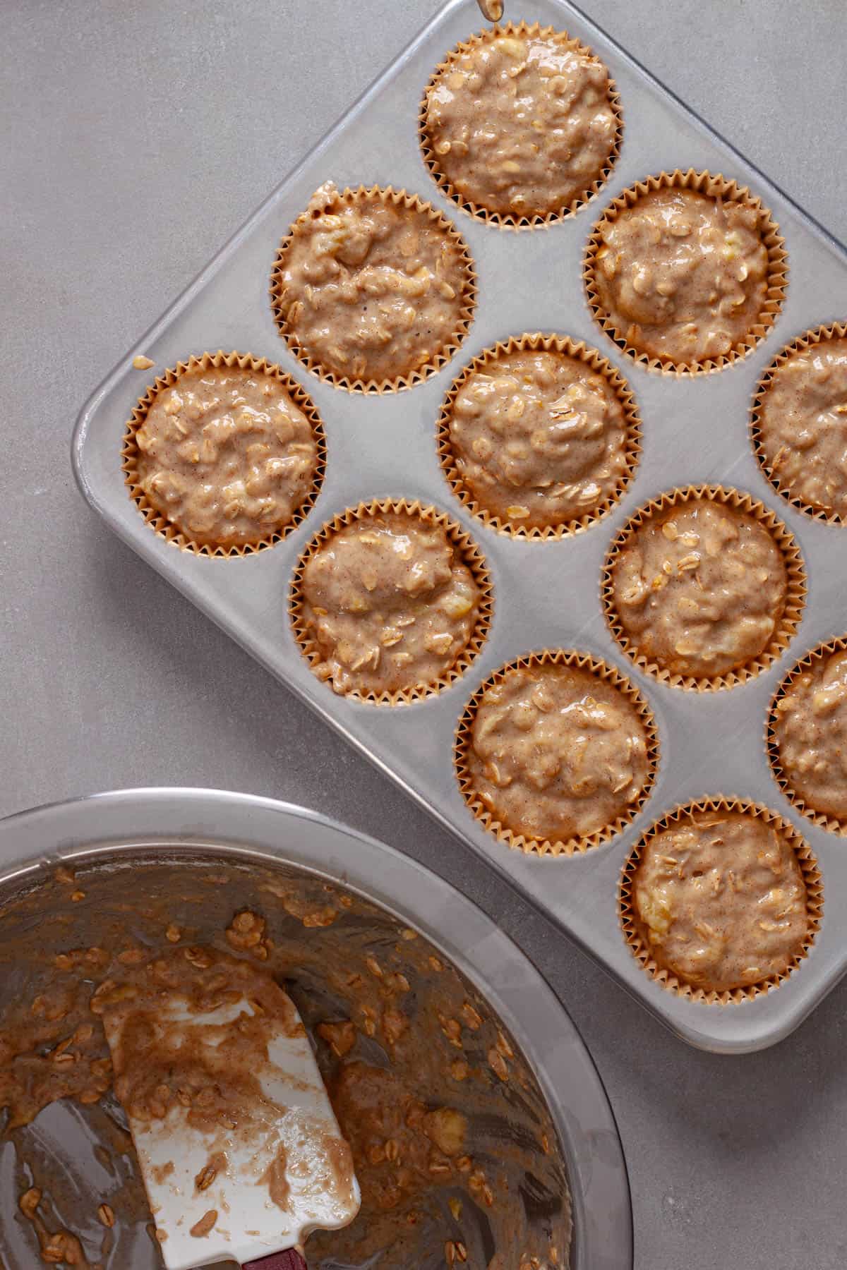 Muffin batter getting added to a muffin tin lined with paper.