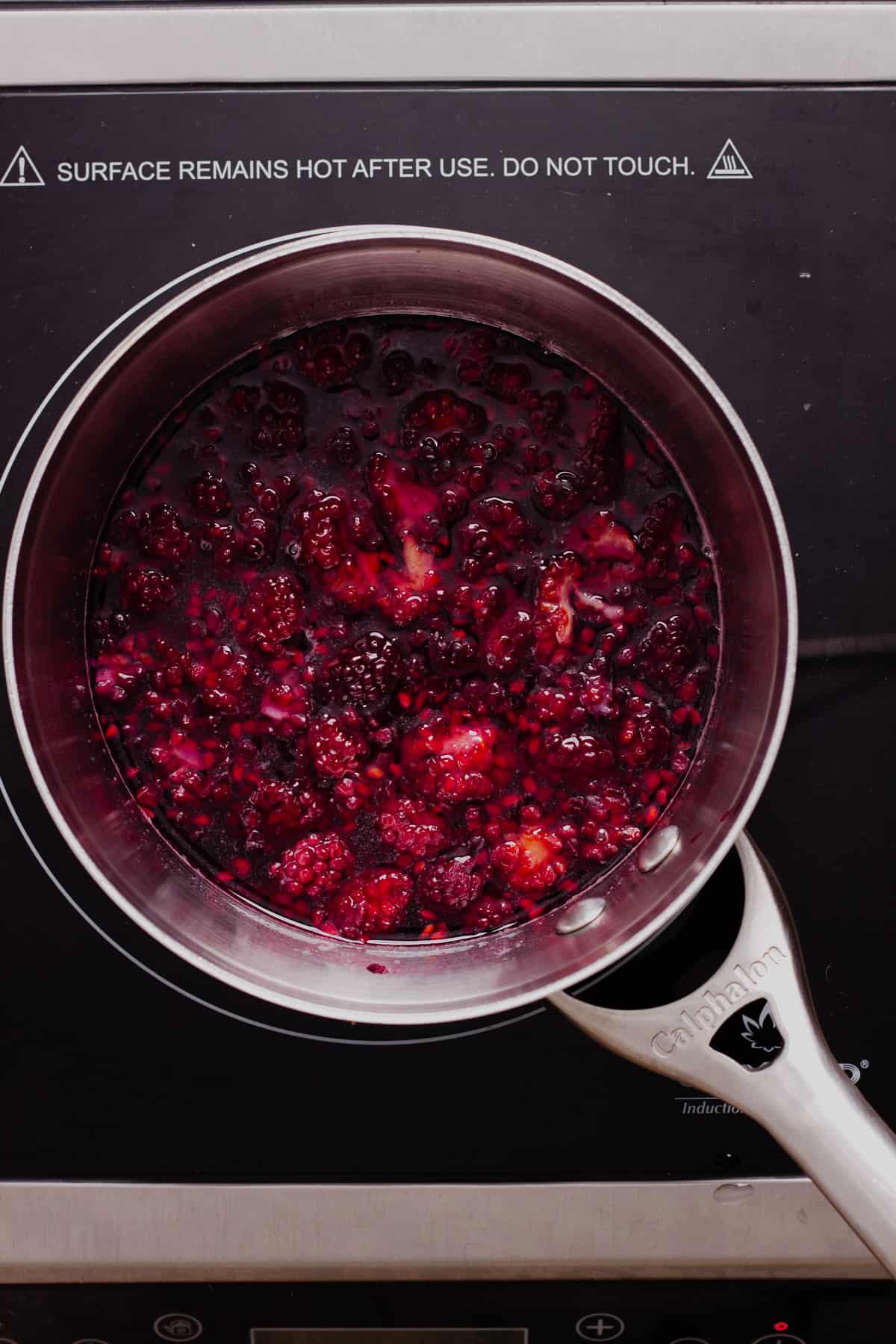 Blackberries and sugar simmering in a small saucepan.