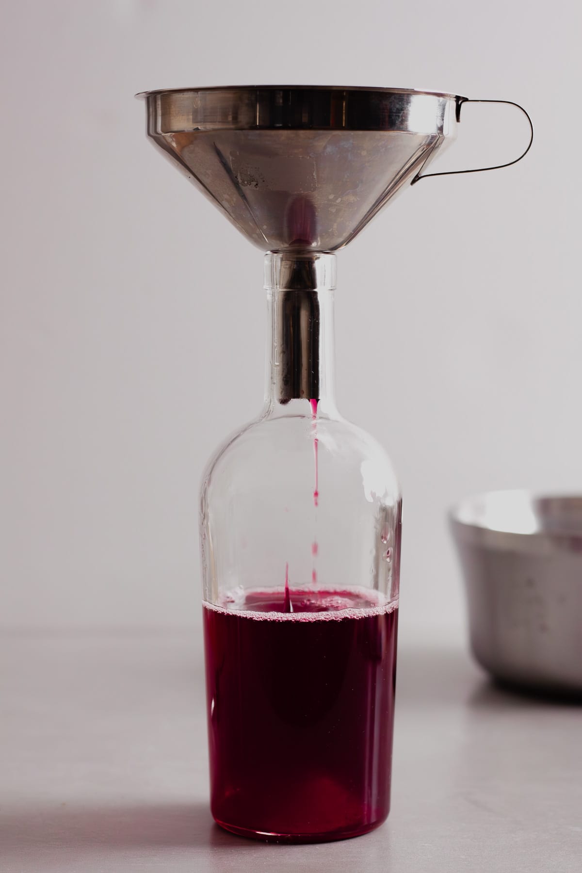 Blackberry simple syrup straining into a glass jar.