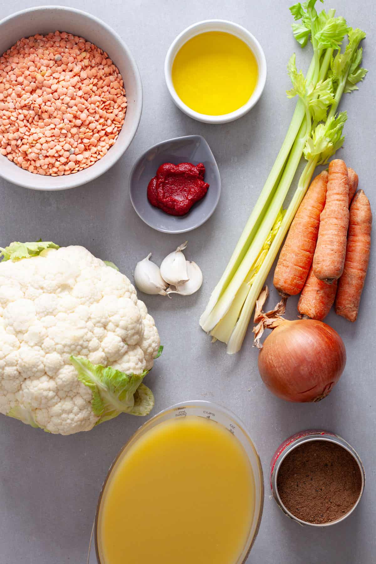 Ingredients for lentil and cauliflower soup on a gray table.