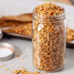 A large mason jar of homemade cinnamon granola on a gray table.