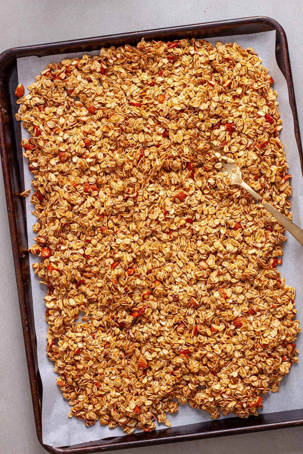 Uncooked cinnamon granola on a parchment lined baking sheet.