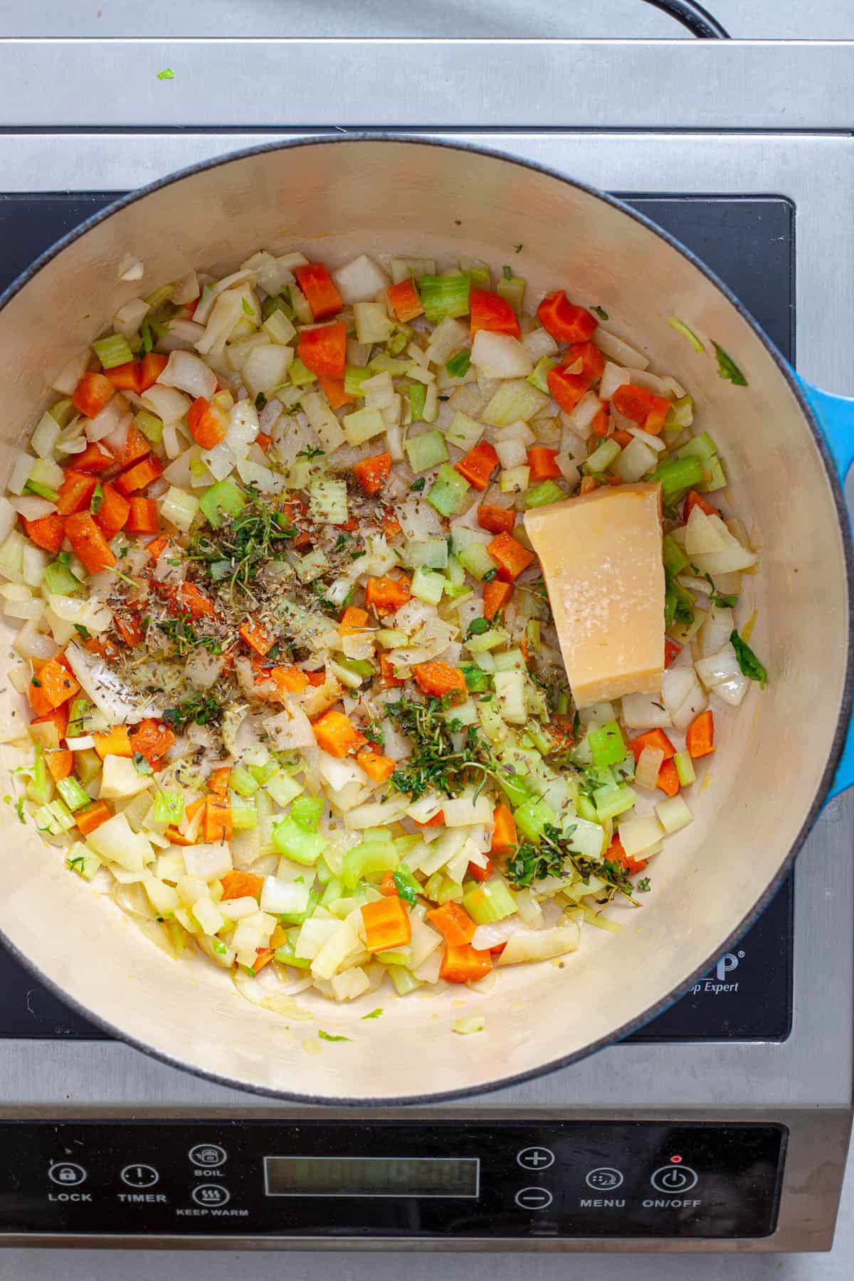 A Dutch oven with vegetables, herbs and parmesan cheese rind cooking.