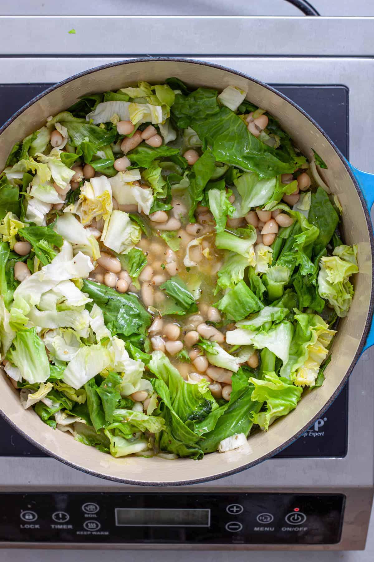 Chopped escarole added to a pot of vegetable soup.
