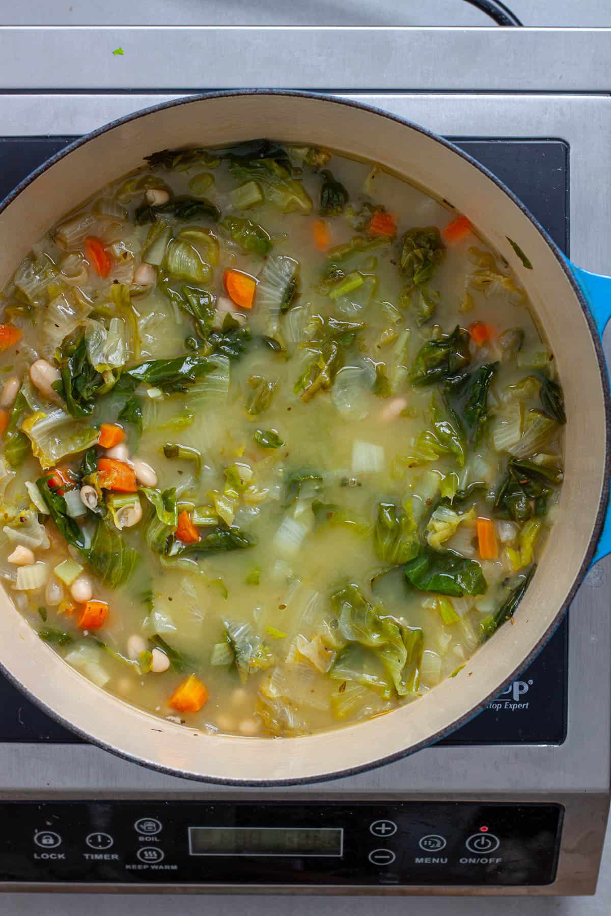 A Dutch oven of escarole and white bean soup simmering.