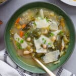 A bowl of escarole and white bean soup with parmesan cheese for garnish.