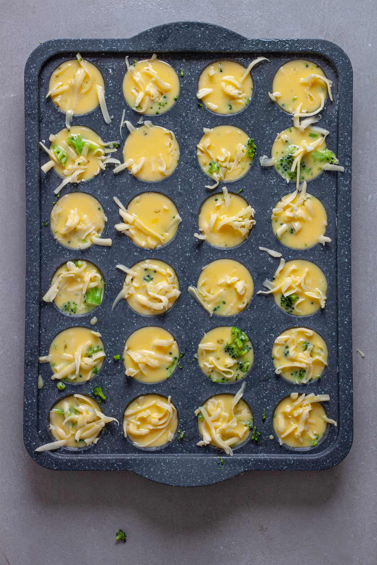Mini egg bites getting assembled in a mini muffin pan.