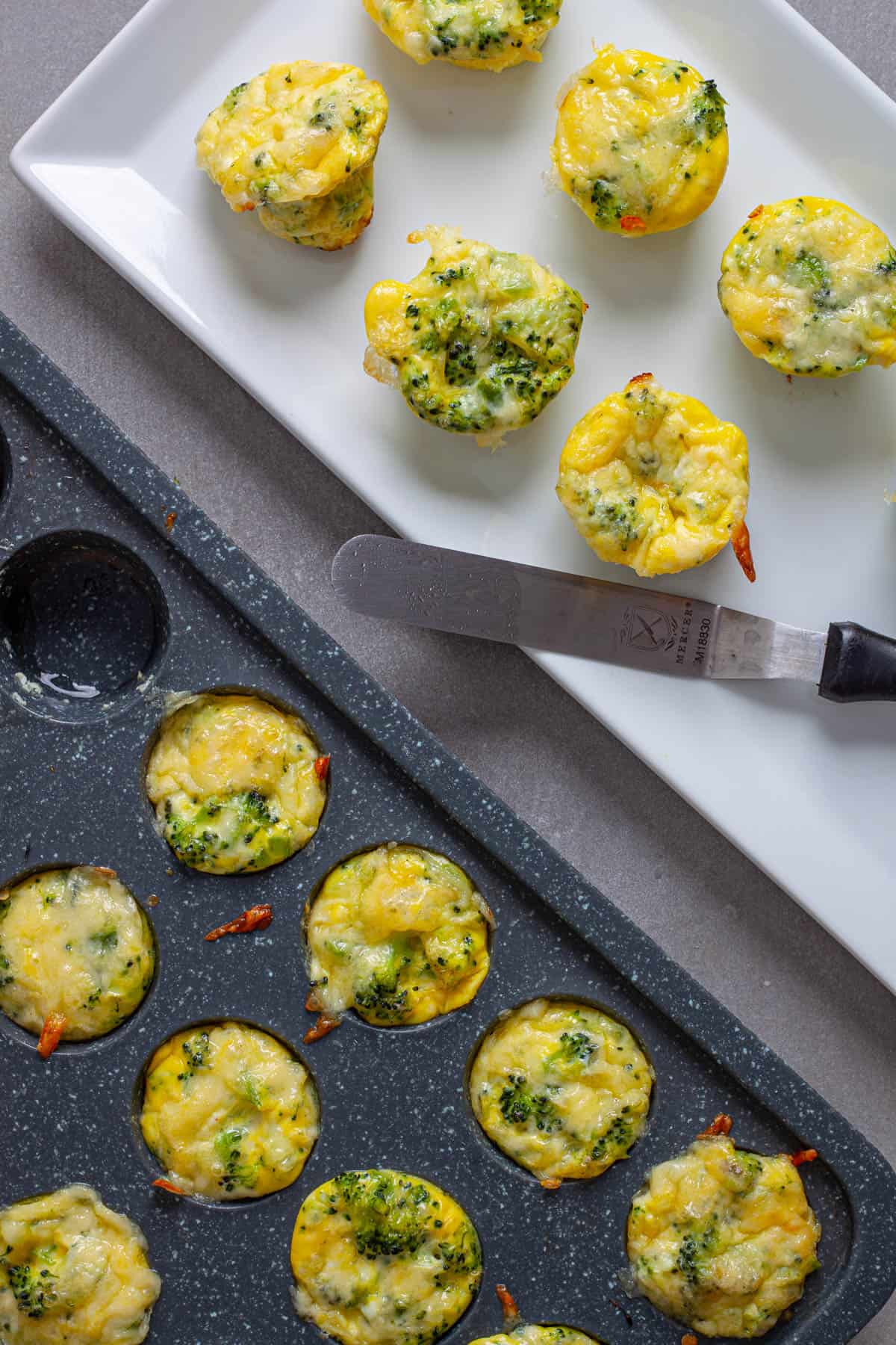 A plate of mini egg bites with broccoli and cheese with a mini muffin with more egg bites to the side.