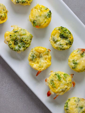 A tray of mini broccoli and cheddar egg bites on a gray table.