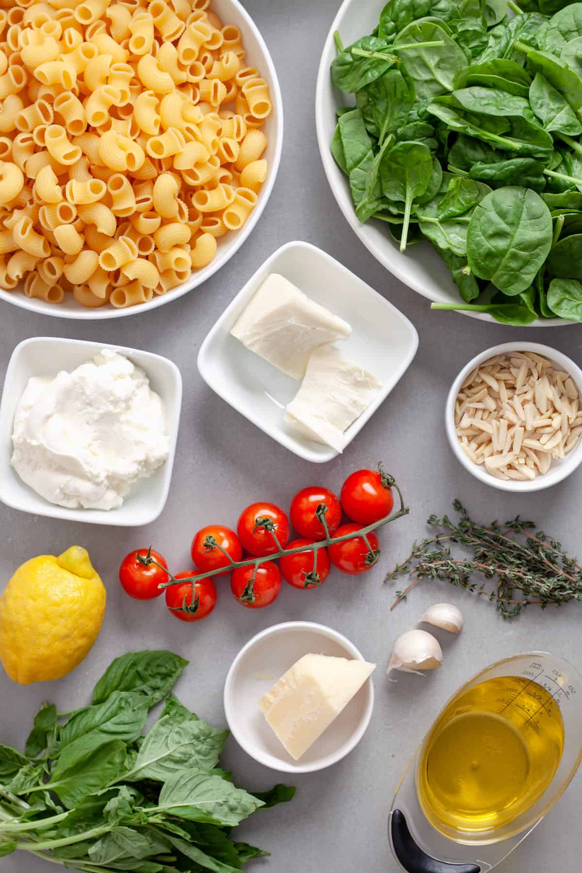 Ingredients for ricotta pesto pasta on a gray table.