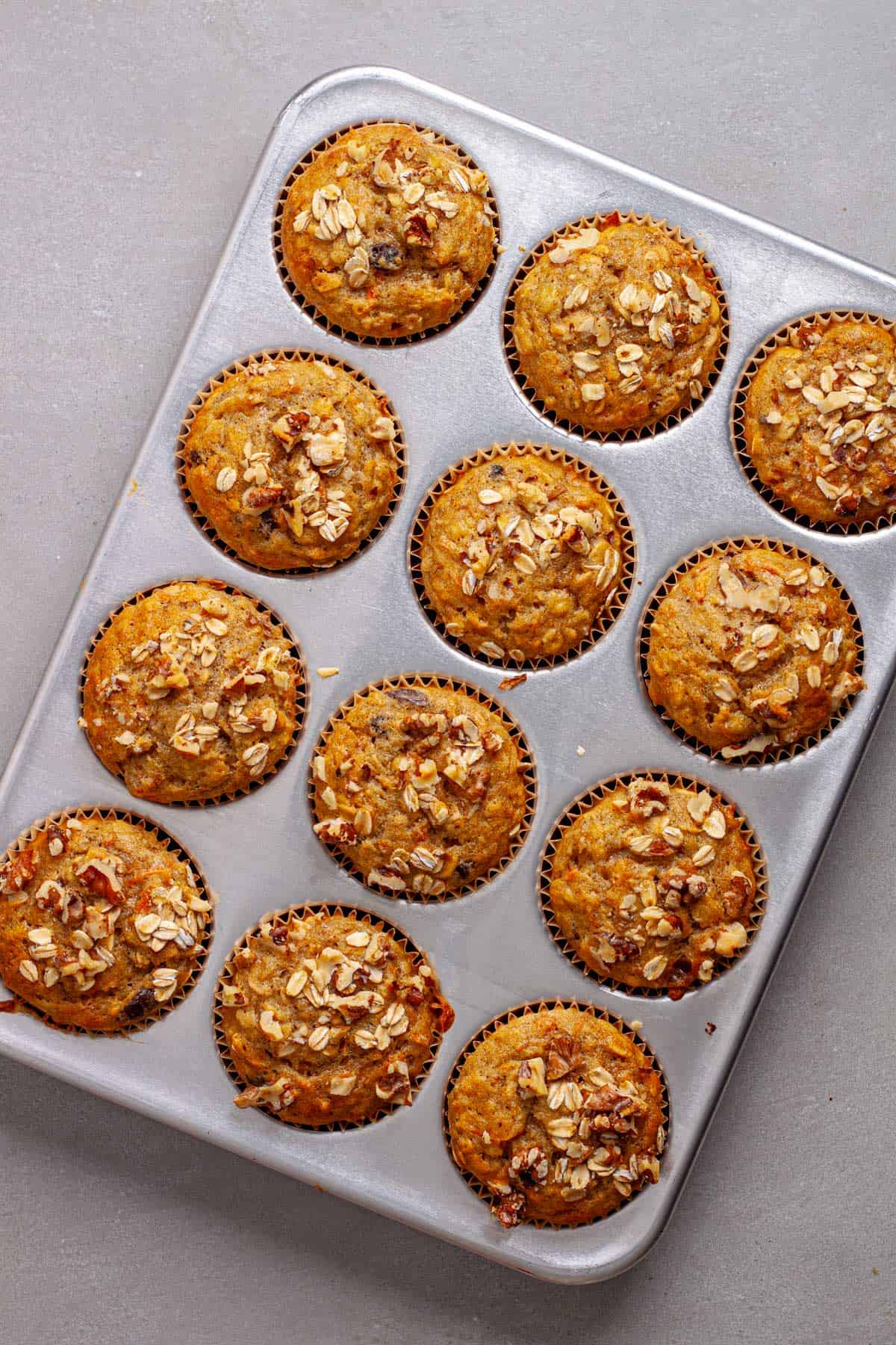 Freshly baked carrot banana muffins on a gray table.