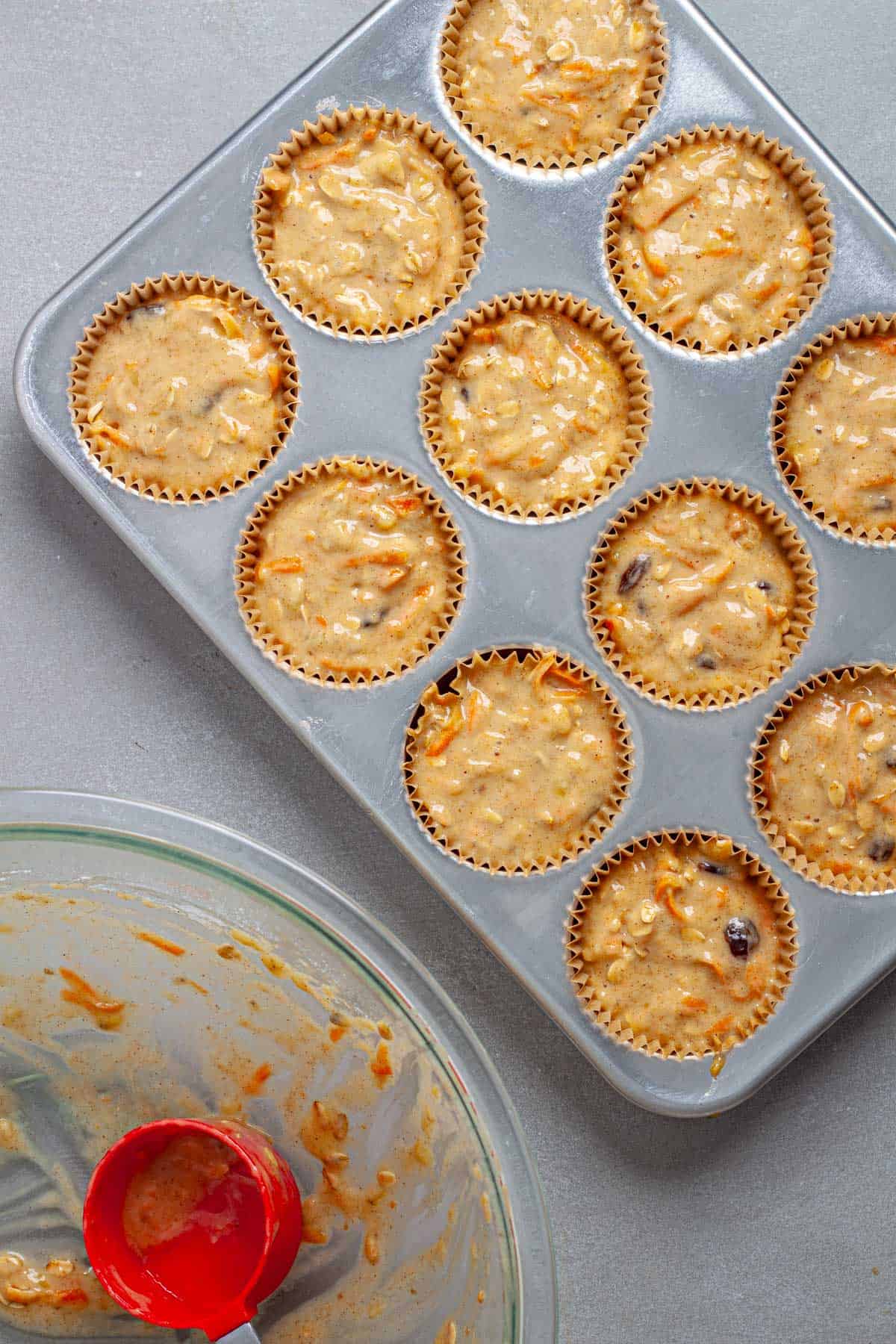 A muffin tin filled with carrot and banana muffin batter.