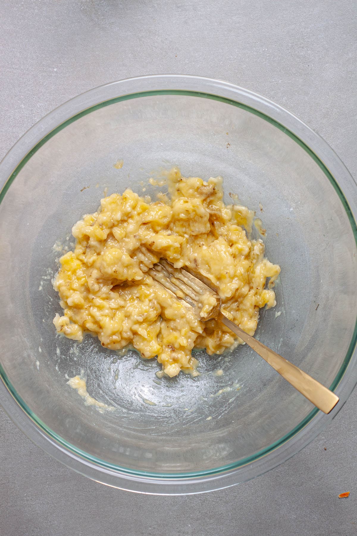 Bananas mashed in a large mixing bowl.
