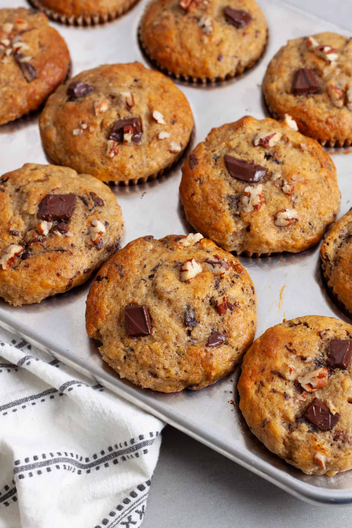 A close up of chocolate chip banana muffins in a metal muffin tin.