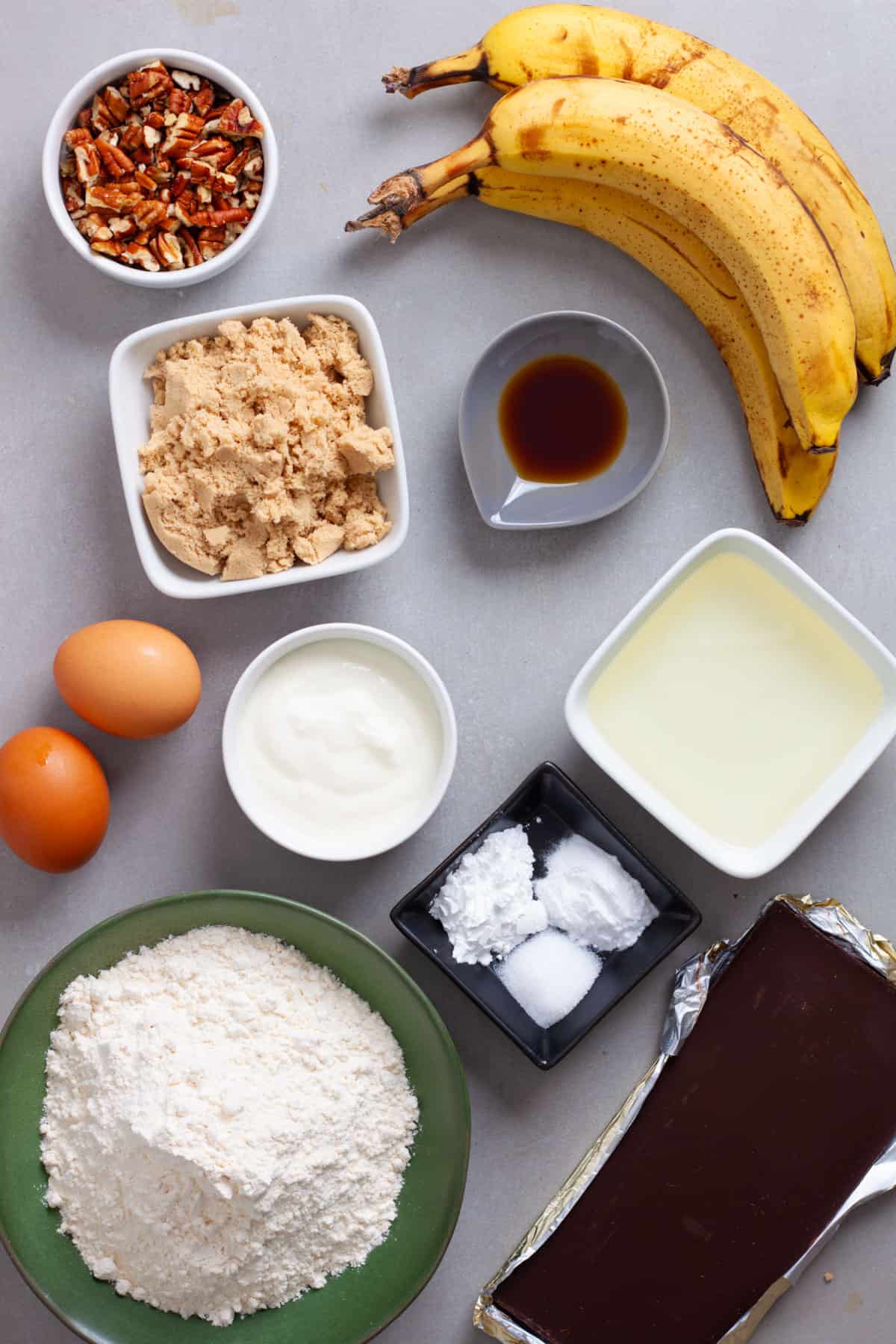 Ingredients for banana chocolate chunk muffins on a gray table.