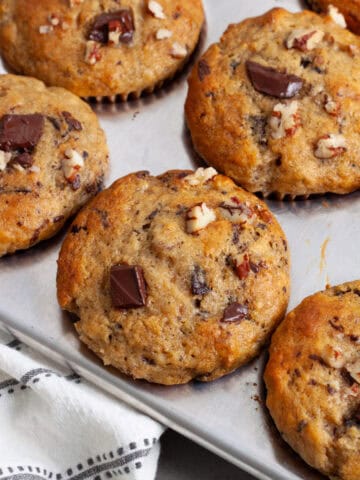 A close up of chocolate chip banana muffins in a metal muffin tin.
