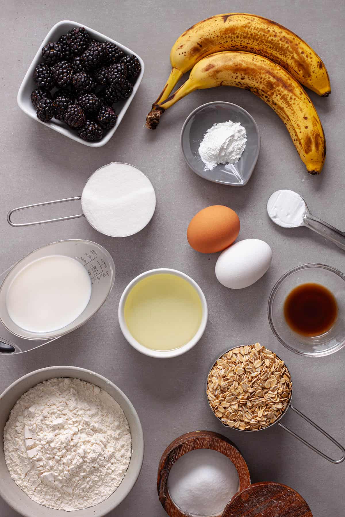 Ingredients for blackberry banana oat muffins on a gray table.