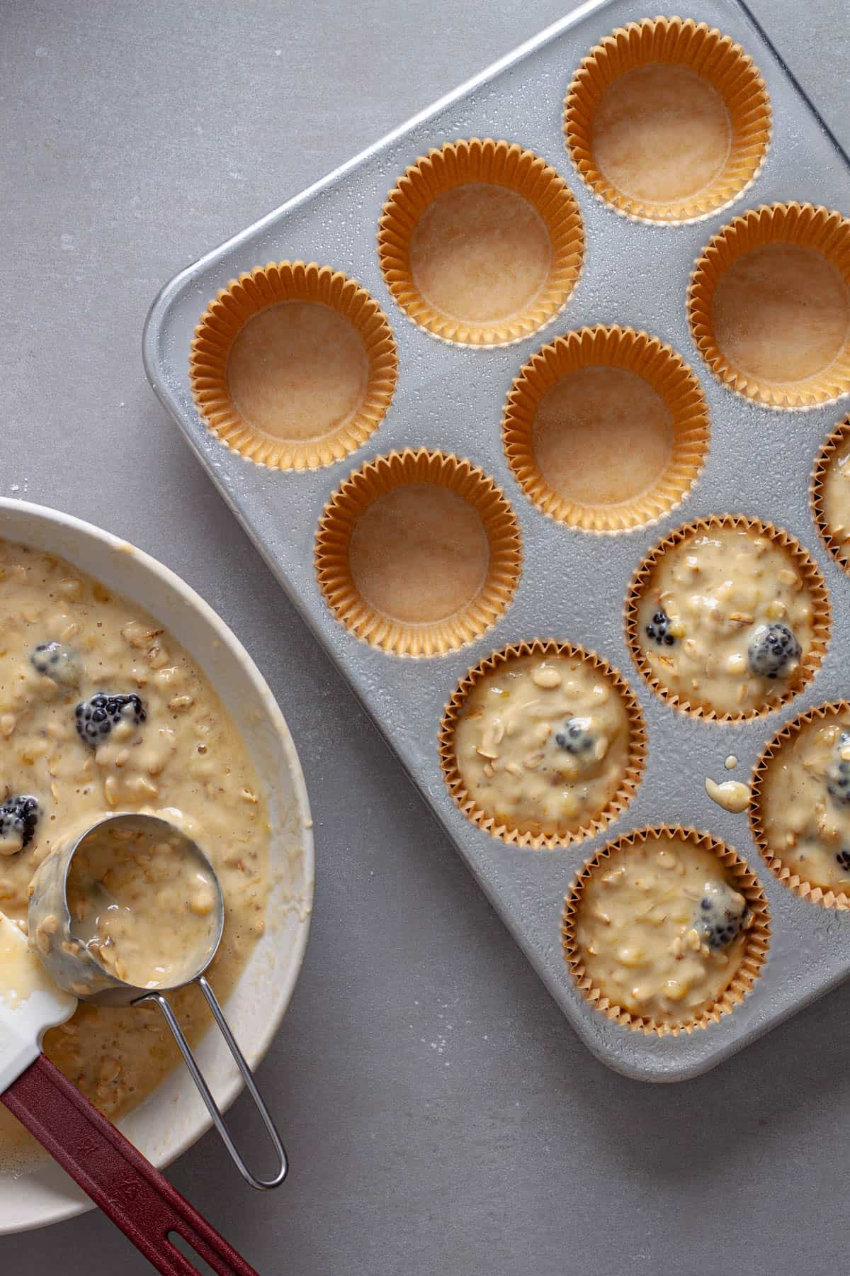 Blackberry oat muffin batter getting added to muffin tins.