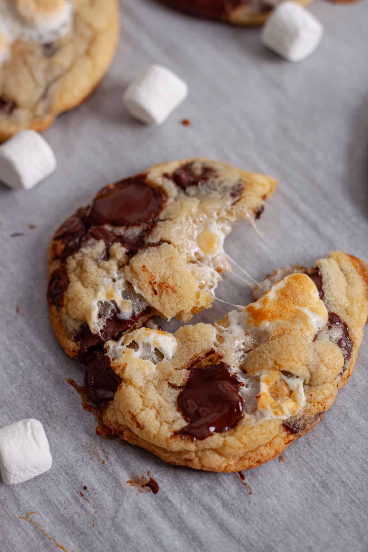 A chocolate chip and marshmallow cookie pulled apart on a baking sheet.