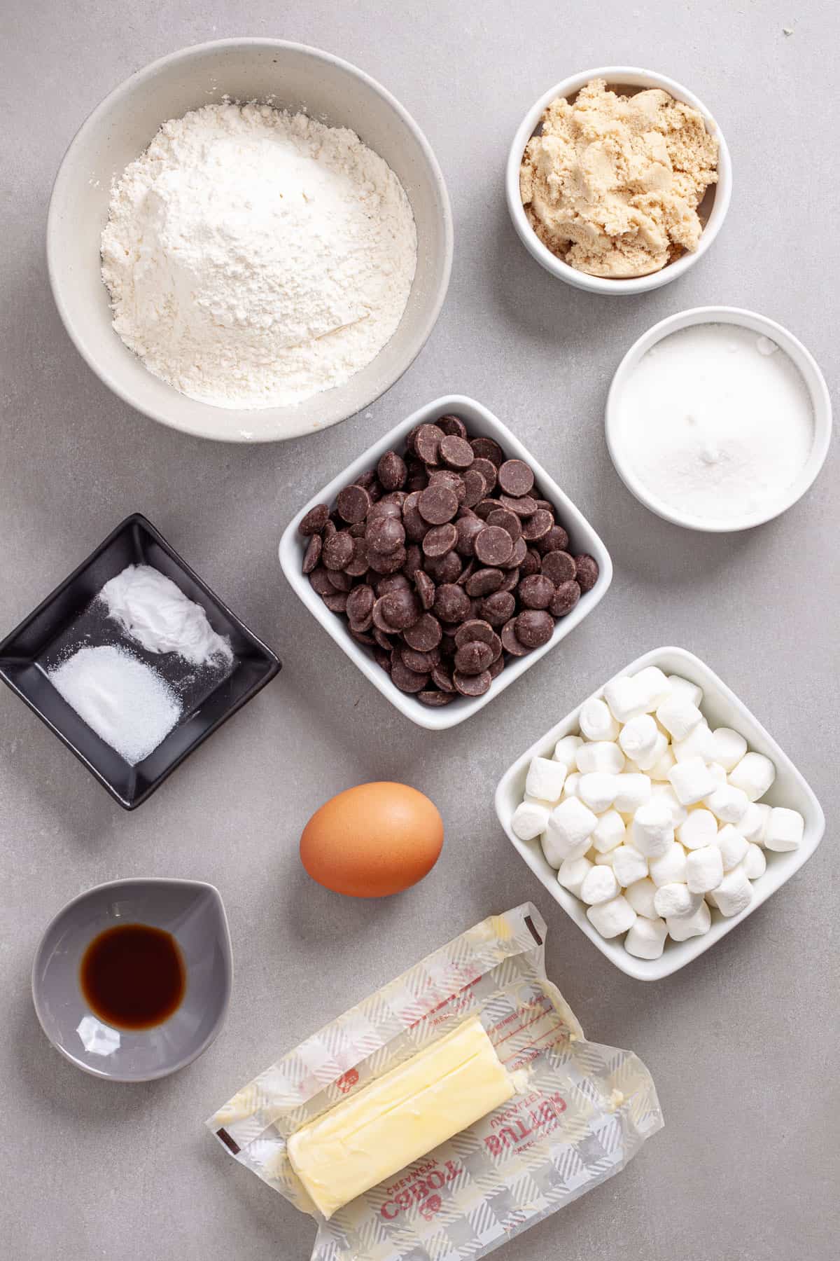 Ingredients for chocolate chip marshmallow cookies on a gray table.