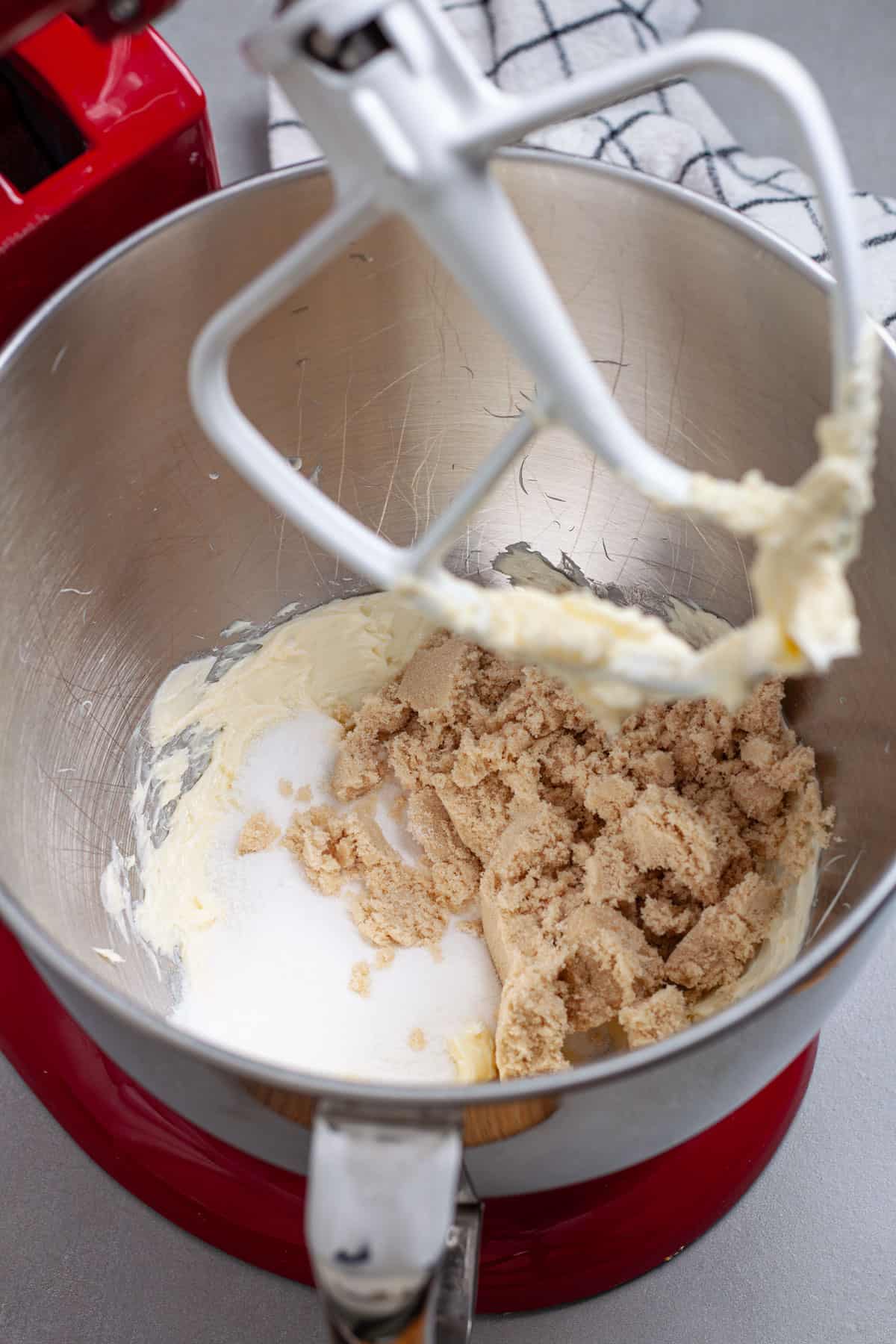 Sugar and brown sugar added to a stand mixer bowl with whipped softened butter.