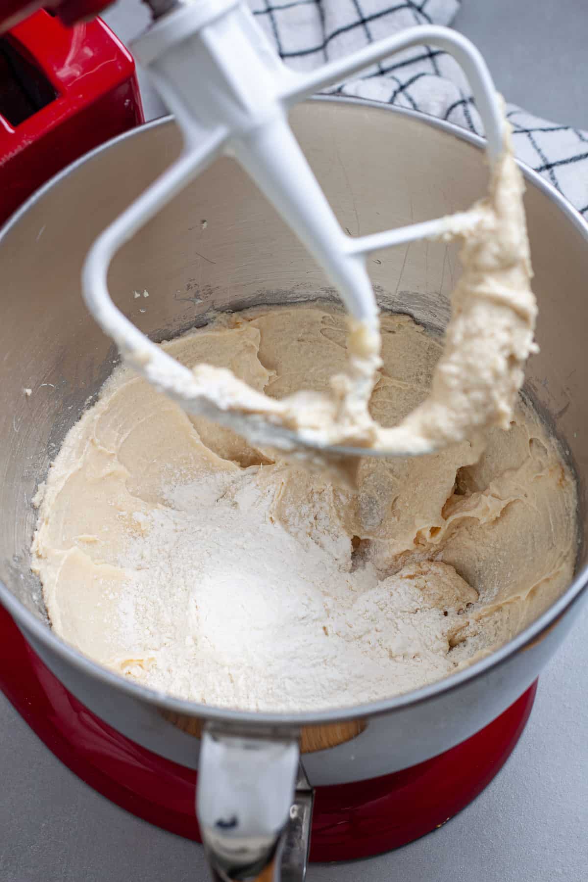 Dry ingredients added to a stand mixer bowl with sugar, butter and eggs.