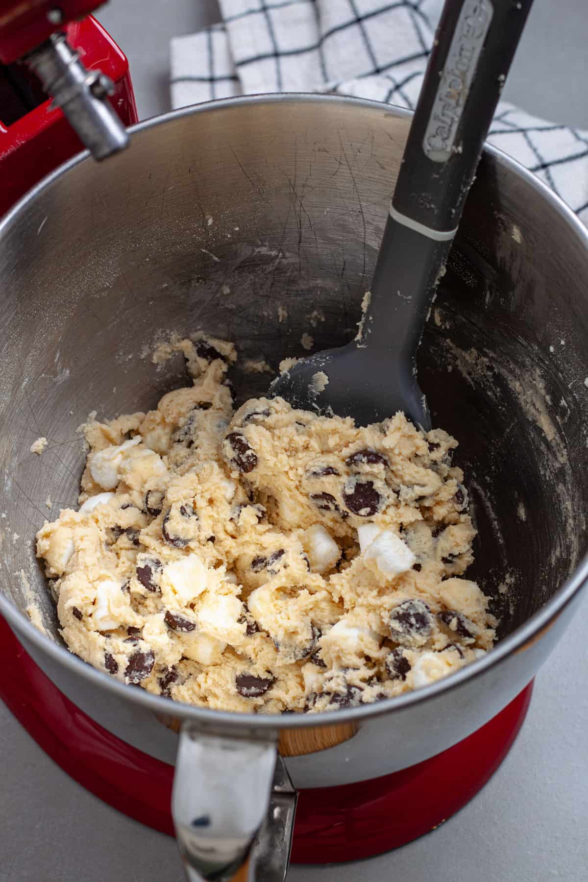 Chocolate chips and mini marshmallows added to cookie dough in a stand mixer.