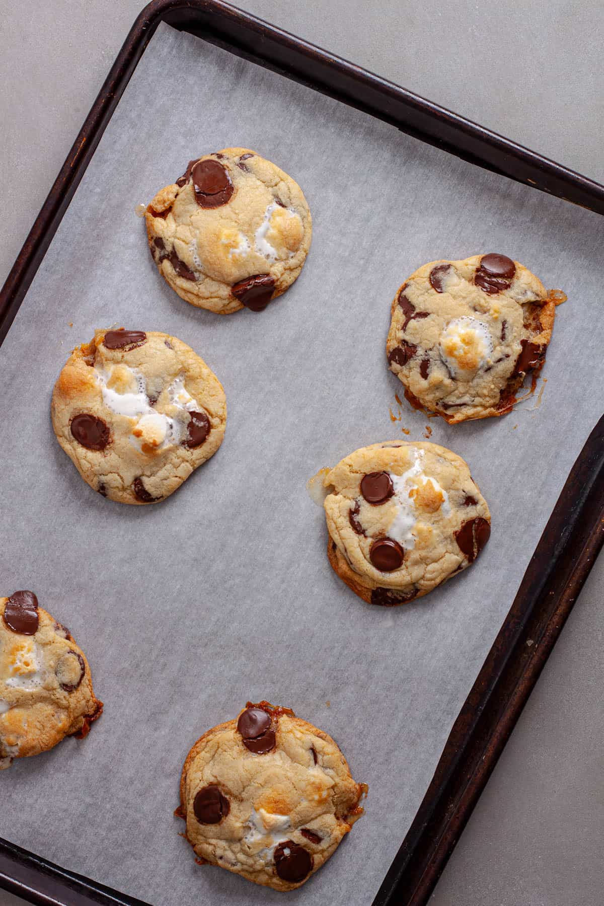 Freshly baked chocolate chip marshmallow cookies on a baking sheet.