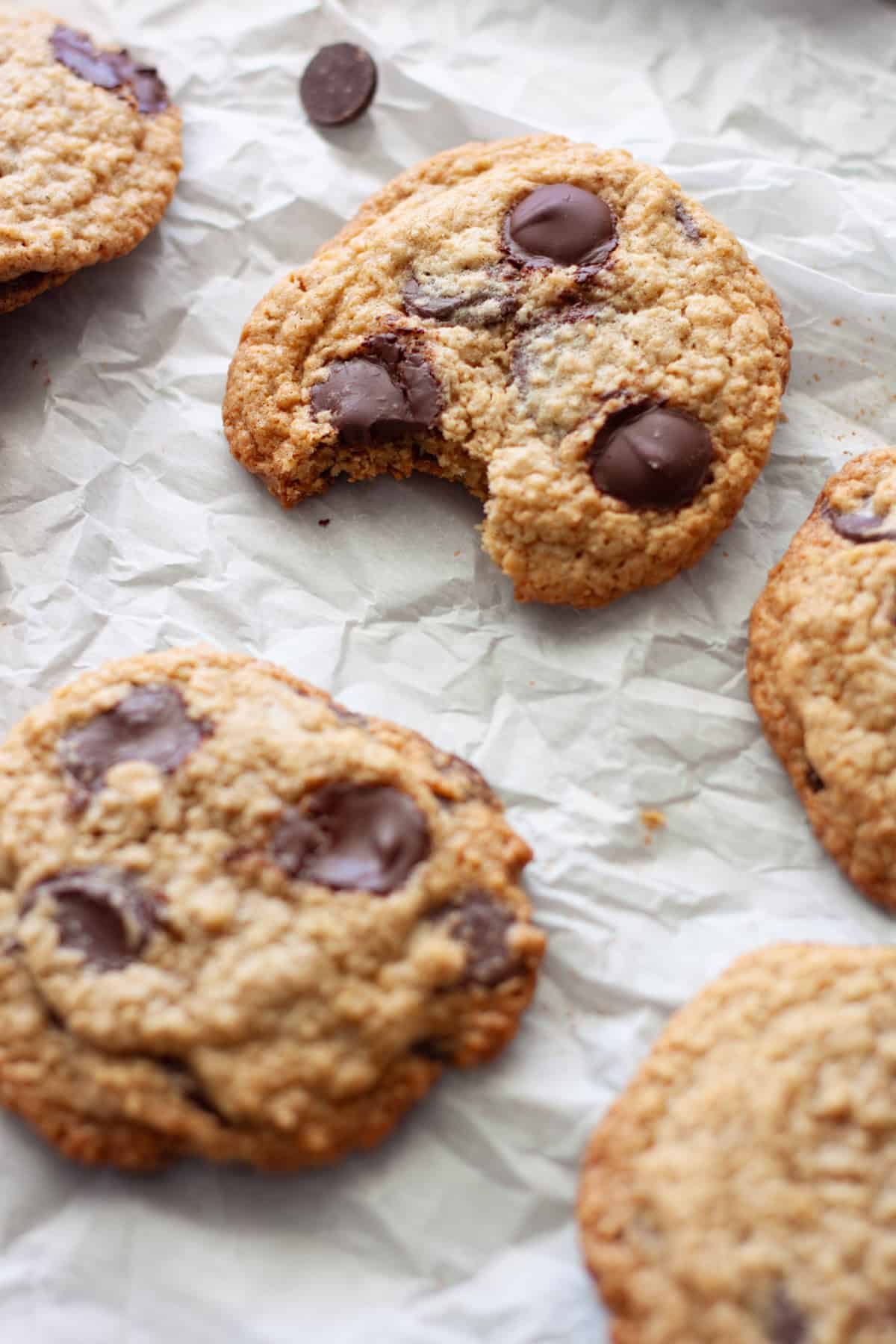 Cookies on a piece of parchment paper with one that has a bite taken out of it toward the back.