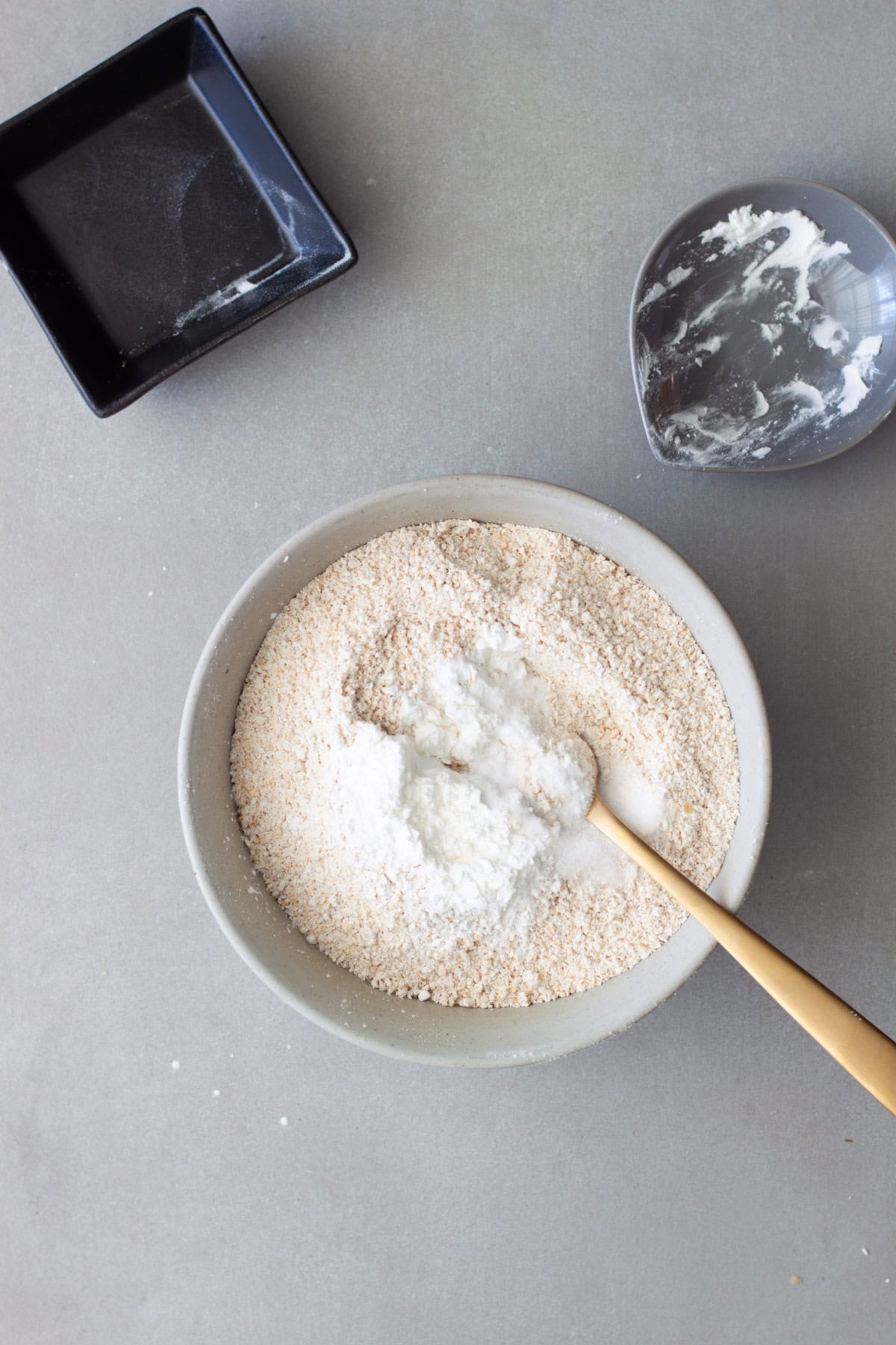 Dry ingredients for oat flour cookies in a medium bowl getting stirred together.
