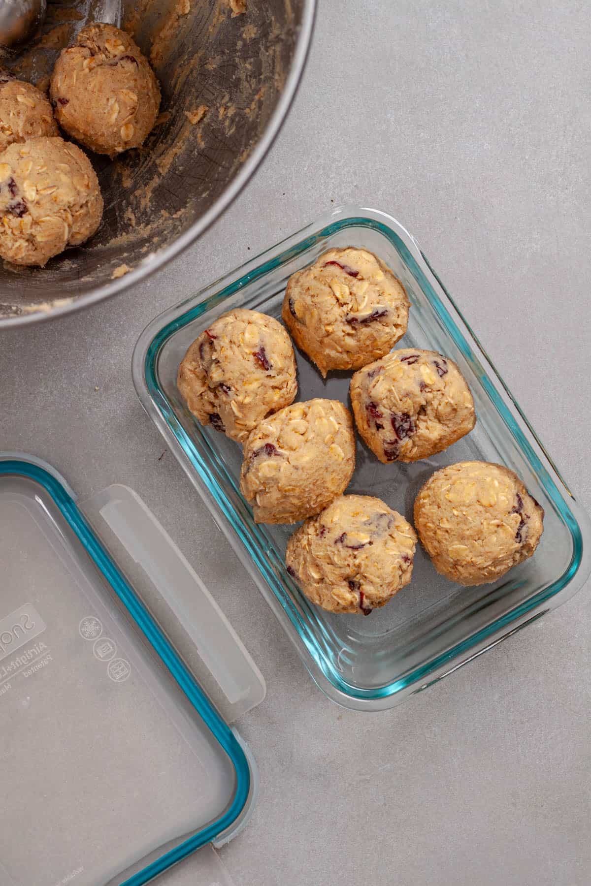 A glass container with portions of oatmeal cherry cookie balls.