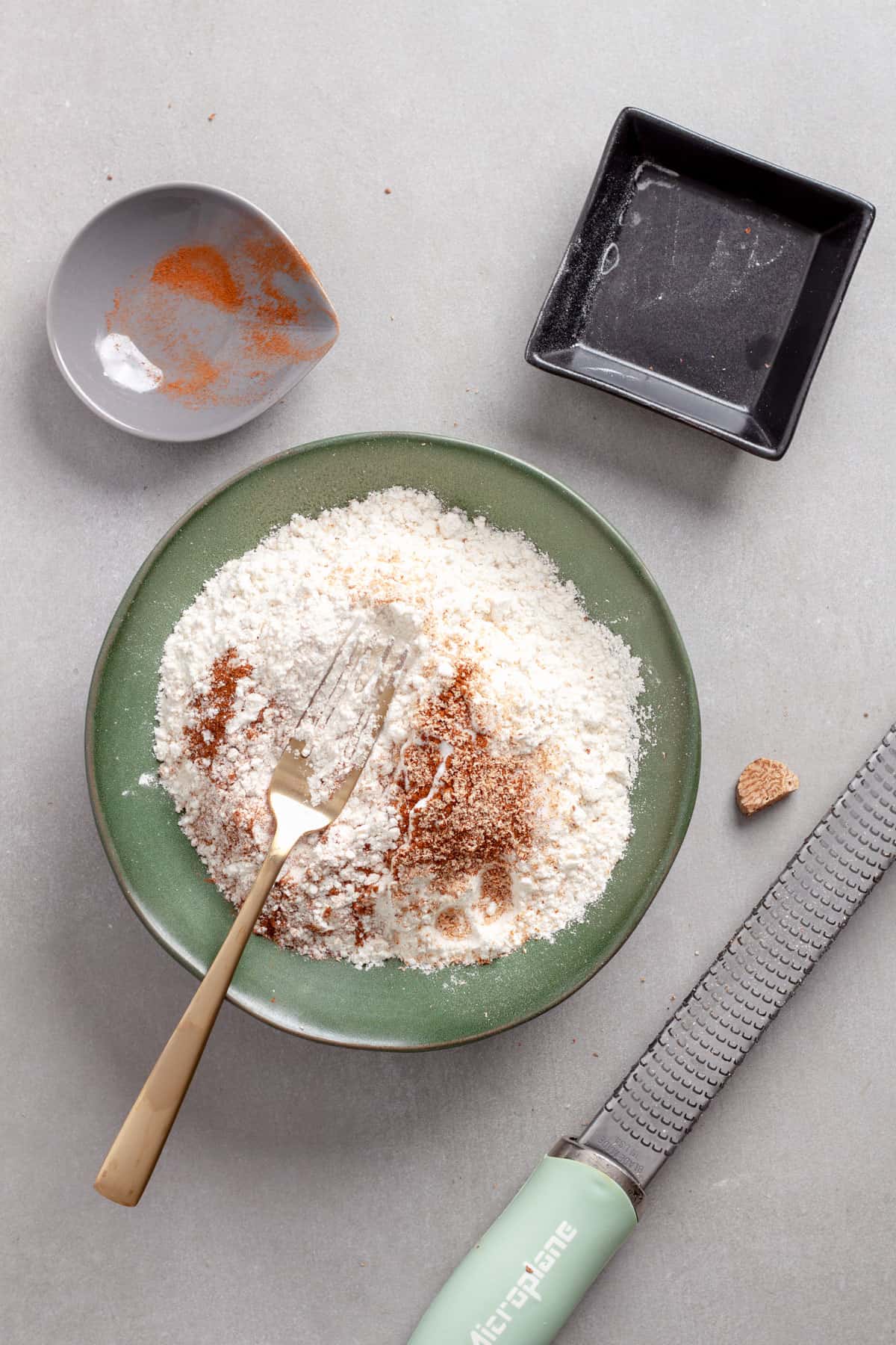 Dry ingredients for cherry oatmeal cookies getting stirred together in a medium green bowl.