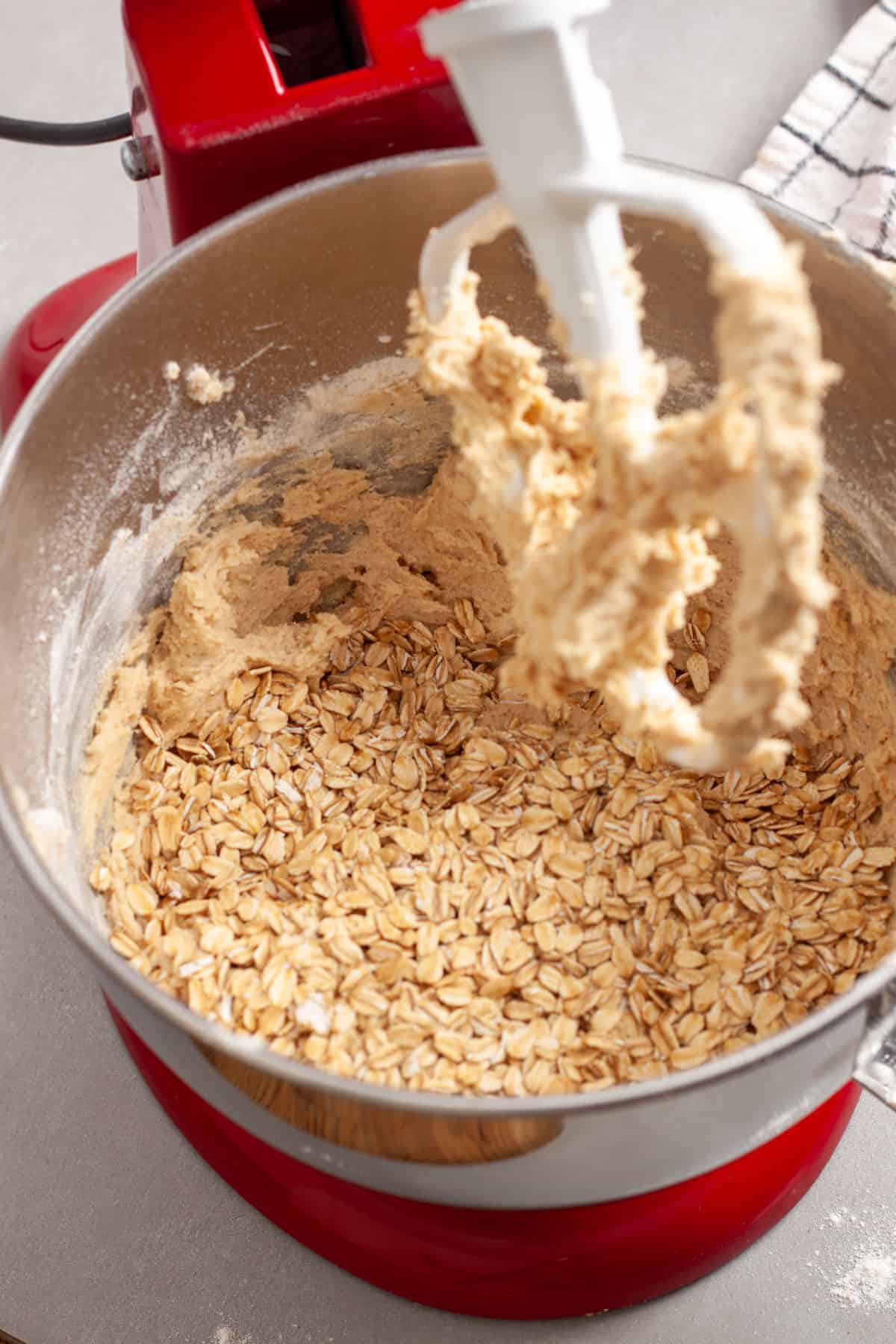 Oats getting added to a stand mixer bowl for cherry oatmeal cookies.