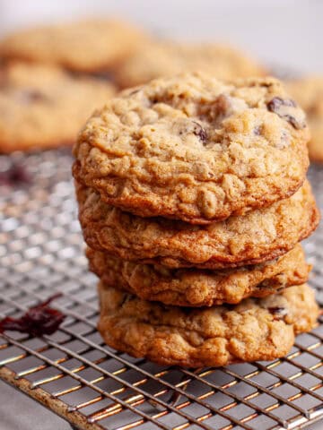 A stack of oatmeal cherry cookies on a wire rack cooling.