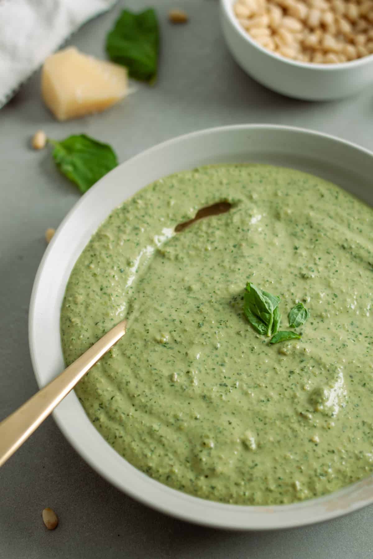A bowl of ricotta pesto sauce topped with fresh basil.