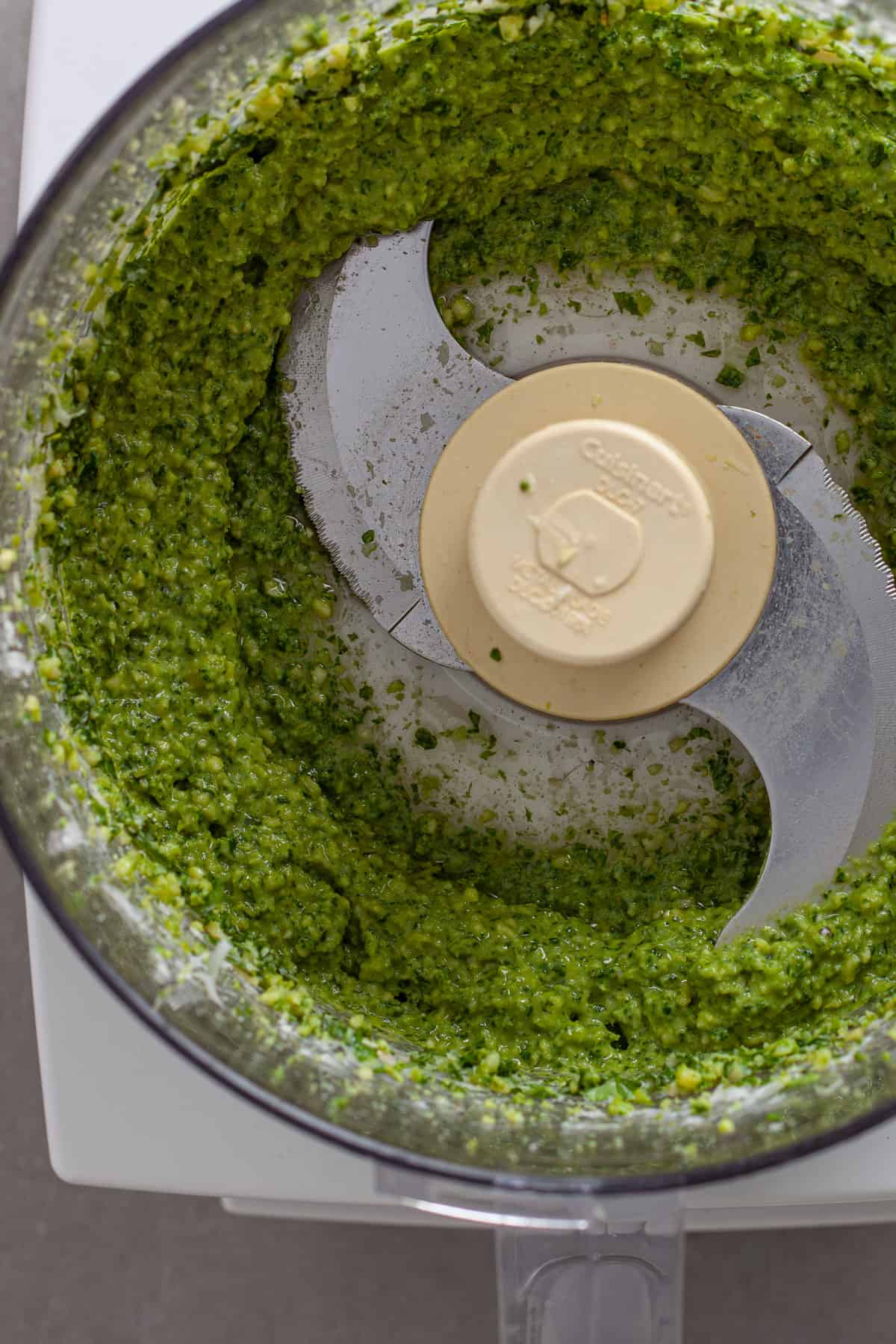 A close up of pesto sauce blended in a food processor.