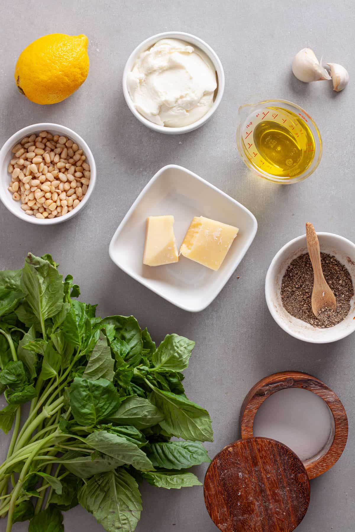 Ingredients for ricotta pesto pasta on a gray table.