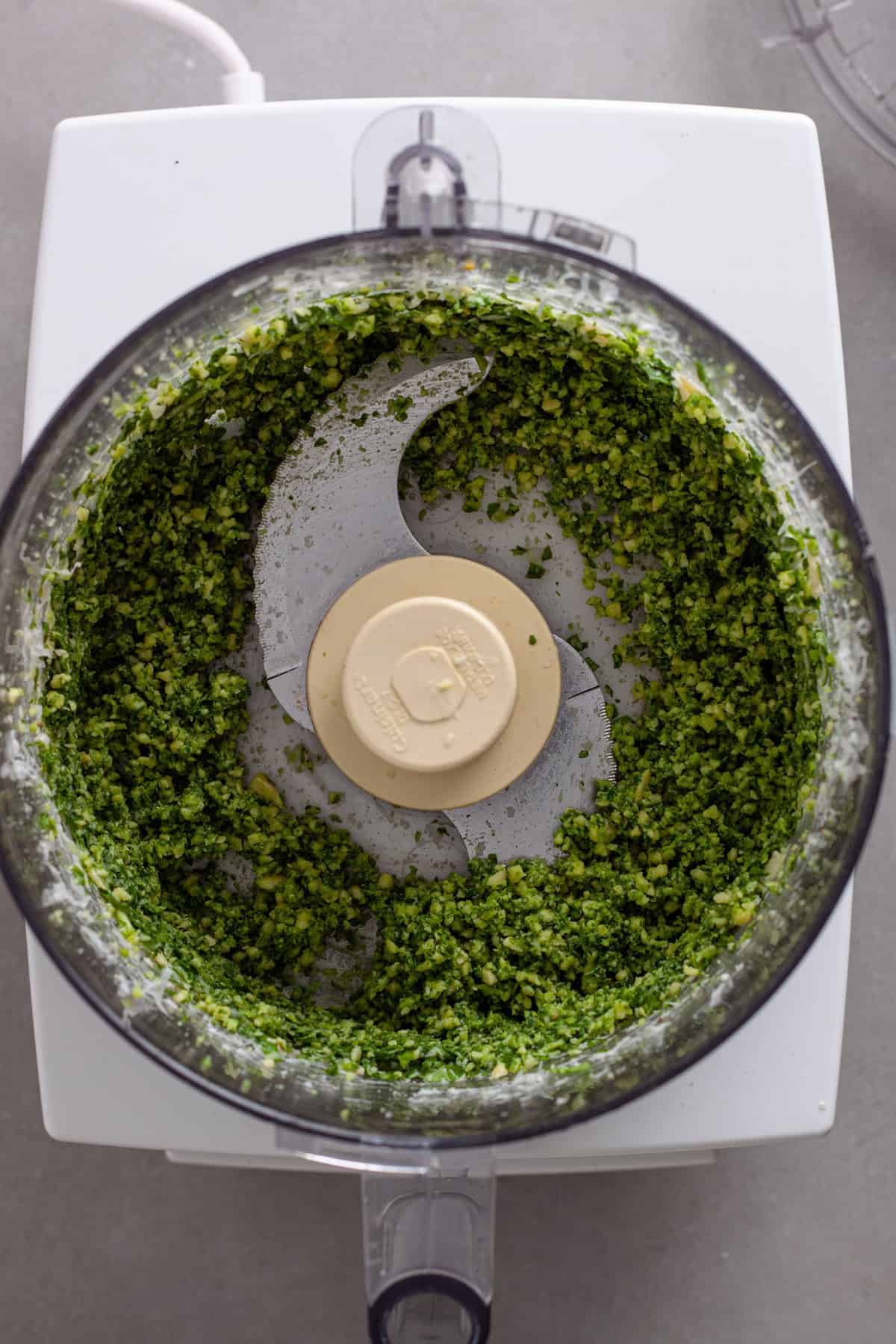 Ingredients for pesto finely chopped in a food processor.