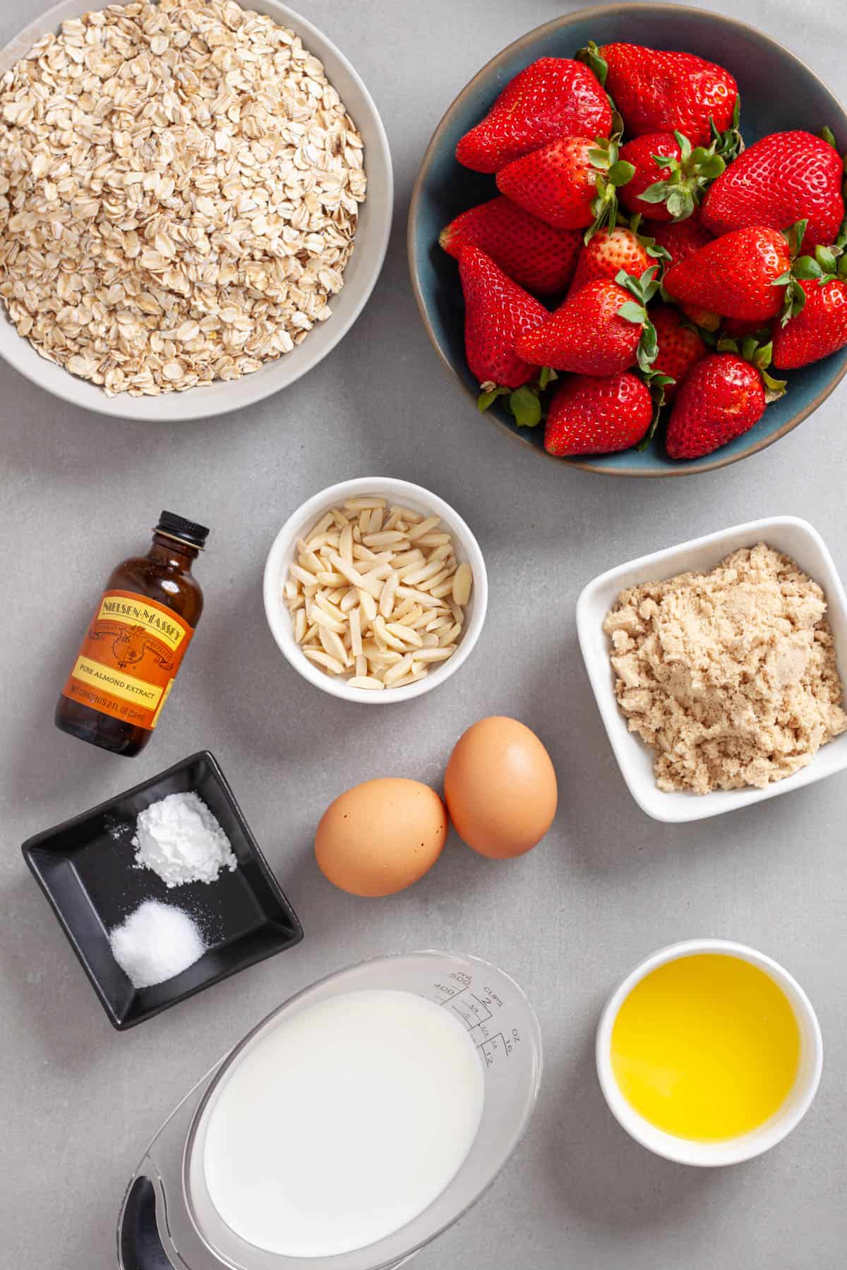 Ingredients for a strawberry and almond baked oatmeal on a gray table.