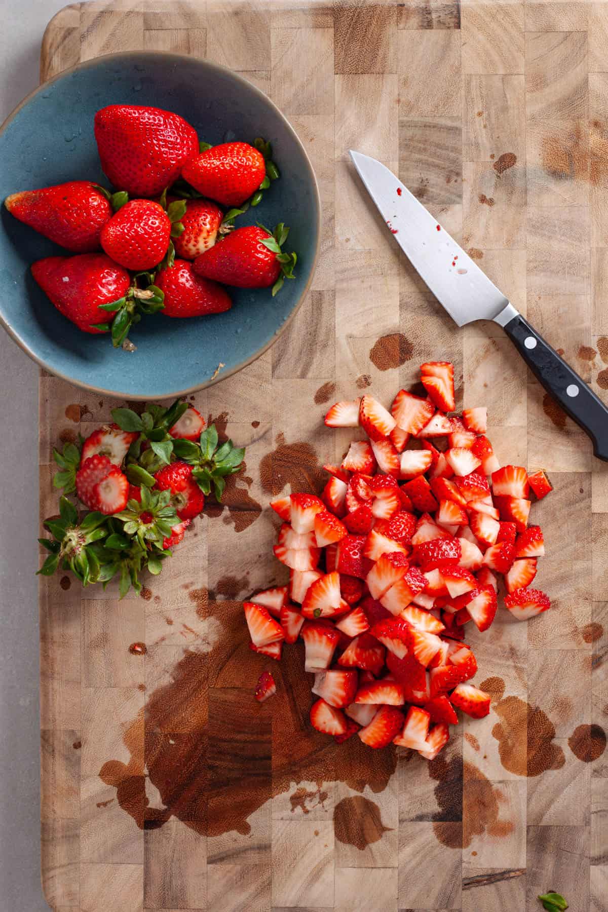 Strawberries chopped on a butcherblock cutting board.