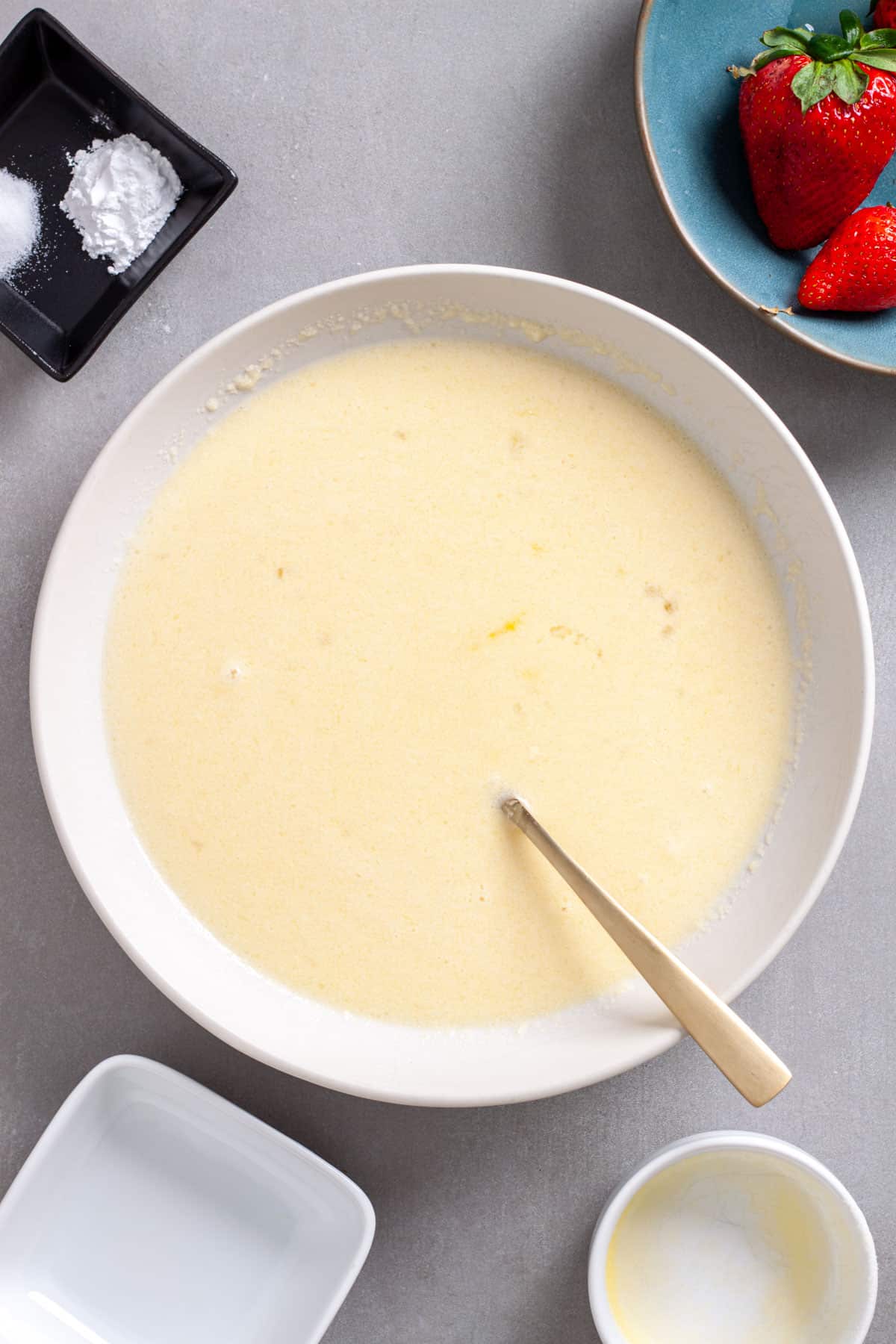 A mixing bowl with wet ingredients for a baked oatmeal on a gray table.