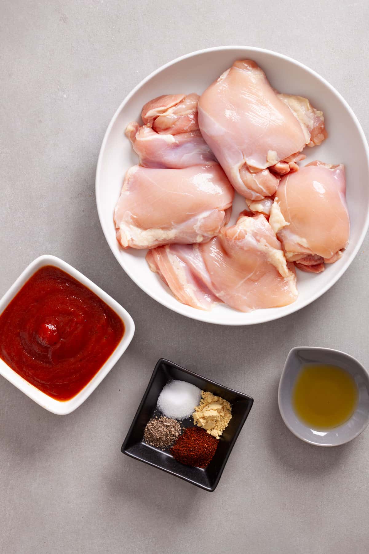 Ingredients for air fryer bbq chicken thighs on a gray table.