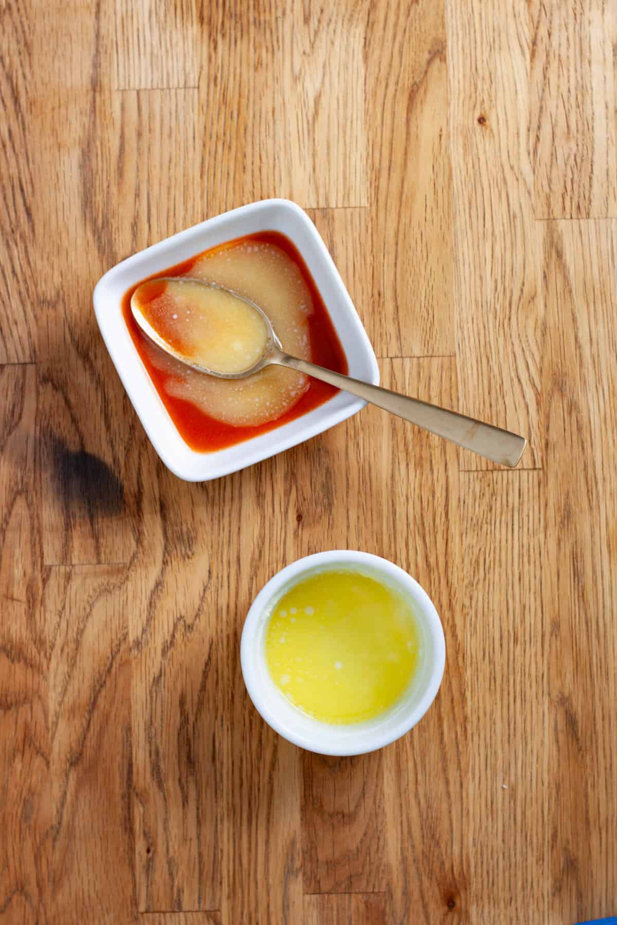 Homemade buffalo sauce in a small bowl on a butcherblock table.