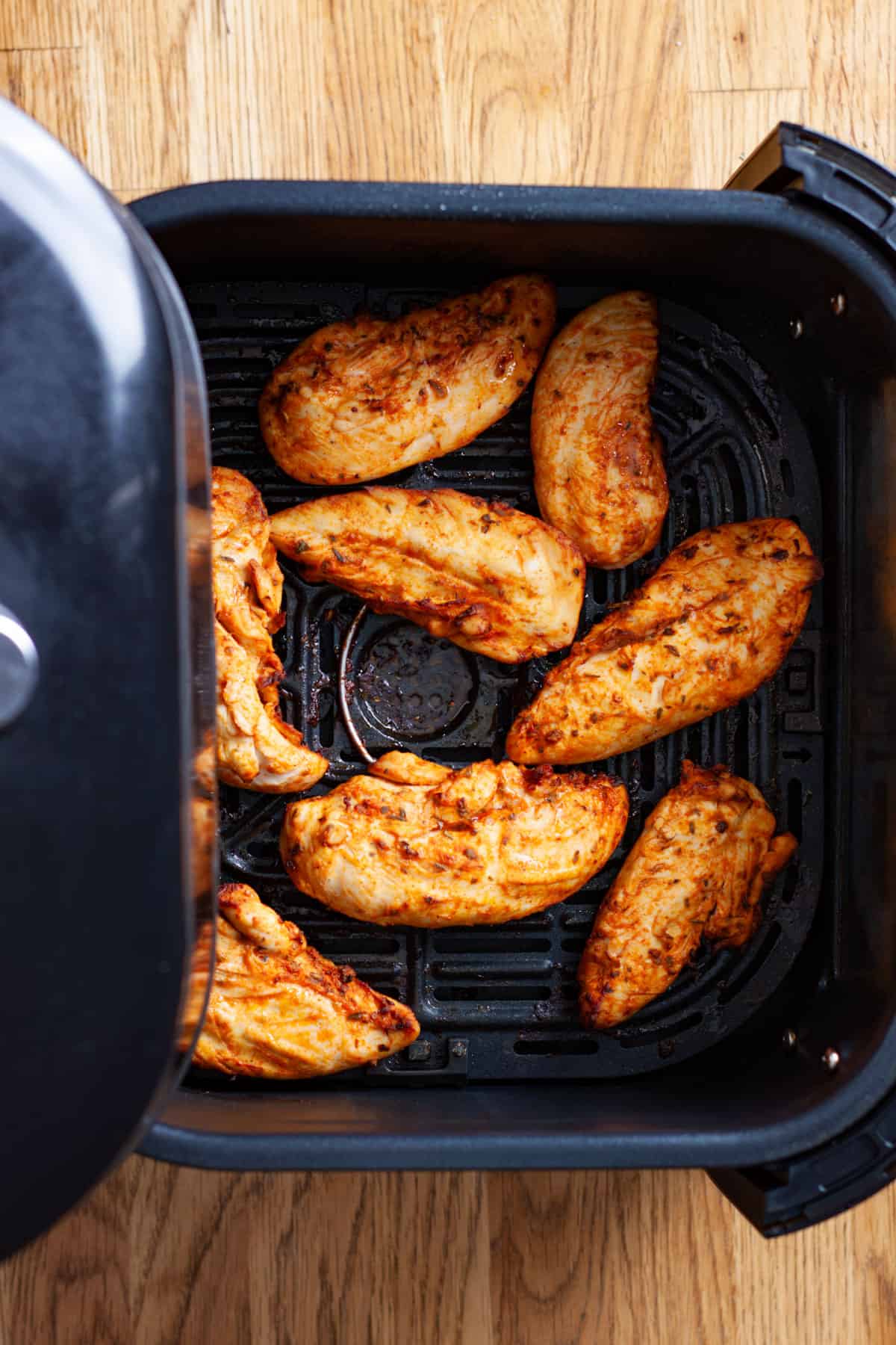 Chicken tenders freshly cooked in the basket of an air fryer.