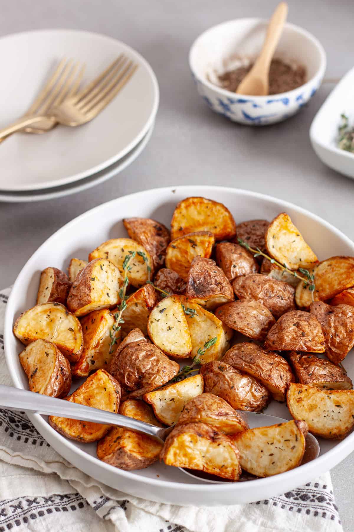 A serving bowl of air fryer red potatoes garnished with fresh thyme sprigs.