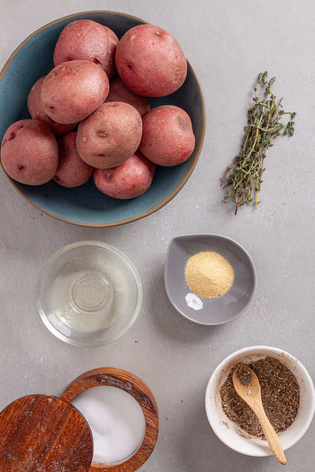 Ingredients for seasoned air fried red potatoes on a gray table.