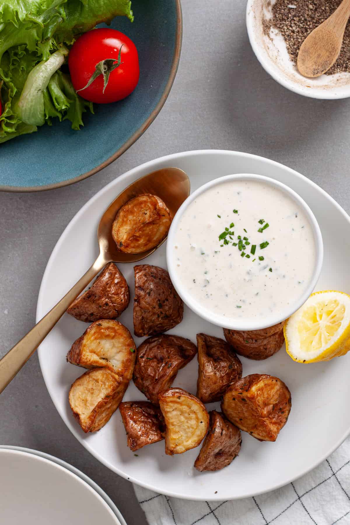 A plate of roasted potatoes with a small bowl of horseradish aioli to the side.